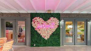 A reception area with a heart-shaped floral arrangement and a neon sign reading "Love Oasis II". - Love Oasis II - Scottsdale Beach Club NEW (Scottsdale)