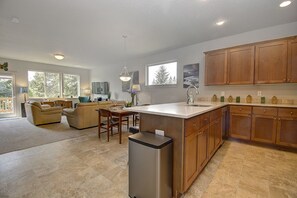 A spacious kitchen with wooden cabinets, a central island, and a dining area with a sofa and chairs.