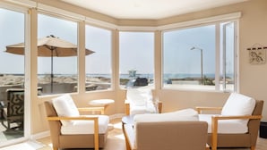 Ein Eckzimmer mit großen Fenstern mit Blick auf einen Strand, ausgestattet mit zwei Sofas und einem kleinen Tisch.