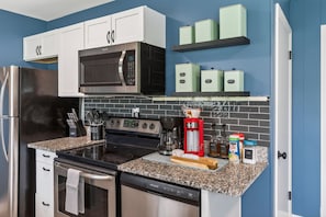 A modern kitchen with stainless steel appliances, white cabinets, and a granite countertop.