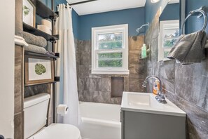 Une salle de bain avec une baignoire, des toilettes, un lavabo et une fenĂȘtre.