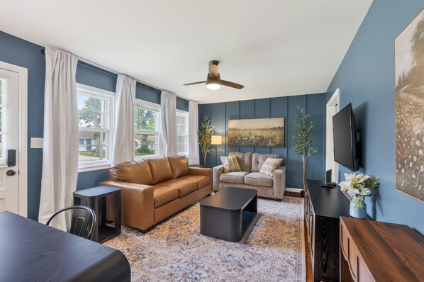 Ein Wohnzimmer mit zwei Sofas, einem Couchtisch, einem Fernseher und einem Deckenventilator.