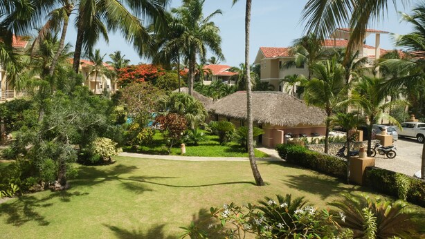 A resort with palm trees, a thatched-roof hut, and a well-maintained lawn. - Home-like studio in Ocean Dream (Cabarete)