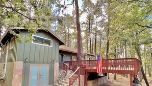 A cabin with a stone staircase leading to a wooden deck, surrounded by trees.