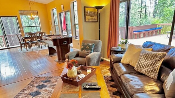 A spacious living area with a wooden coffee table, leather sofa, and a dining table with chairs.