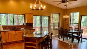 A spacious kitchen with wooden cabinets, a large island, and a dining area with a table and chairs.