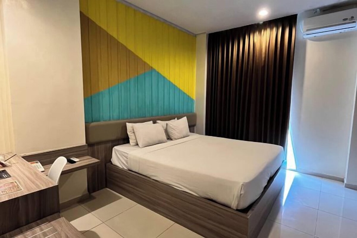 A hotel room with a bed, a desk, and a chair.