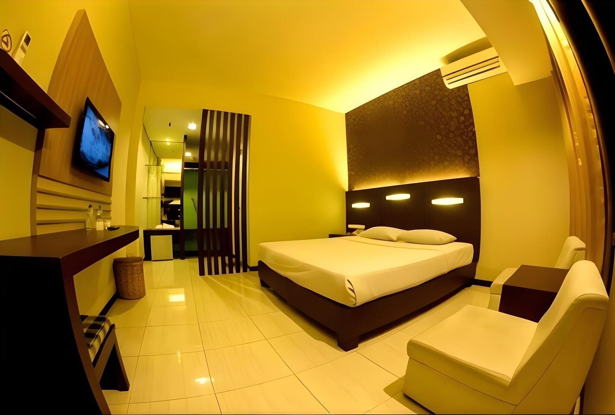 A hotel room with a bed, a TV, a desk, and a chair.