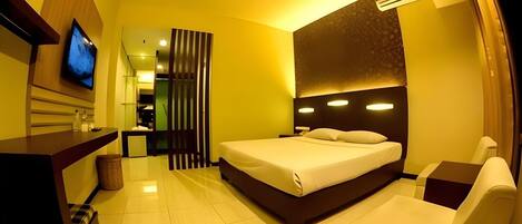 A hotel room with a bed, a TV, a desk, and a chair.
