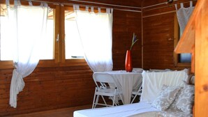 A wooden cabin room with a bed, a table, and two chairs. - villa chalet con piscina (Palermo)