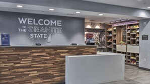 A reception area with a 'Welcome to the Granite State' sign, a reception desk, and a well-organized suite shop. - Hampton Inn & Suites Keene (Keene)