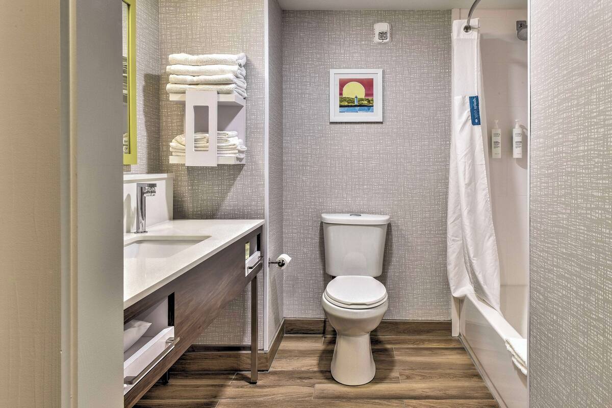 A compact bathroom with a toilet, sink, and shower area.