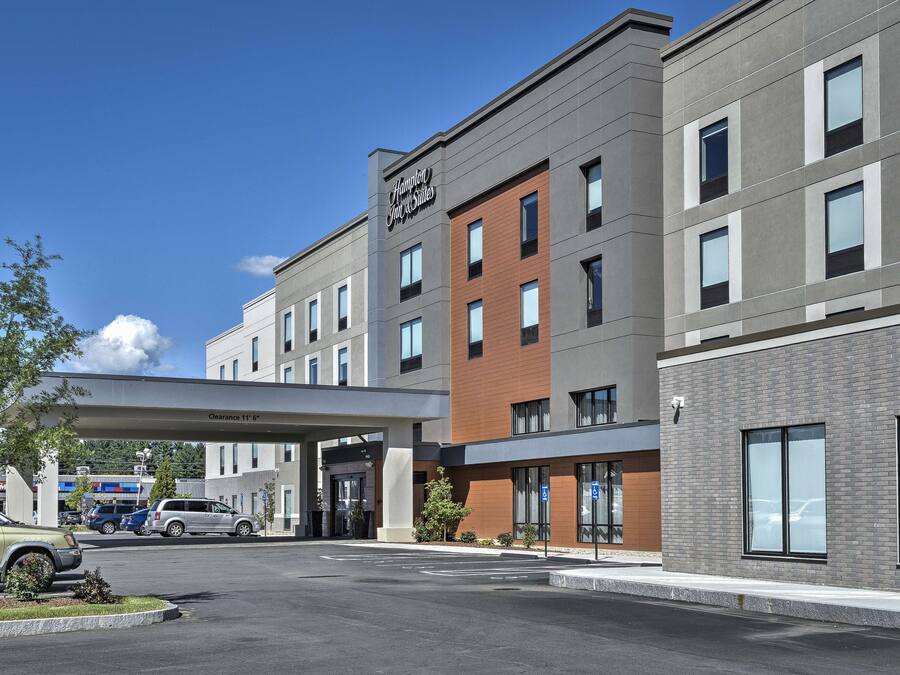 A modern hotel with a clear entrance, a parking area, and a sign indicating a 11' clearance.