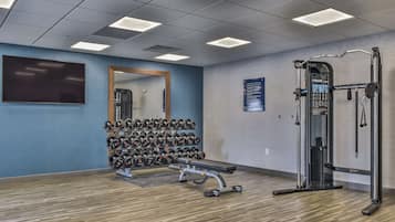 Un gimnasio con banco, mancuernas y una estructura para sentadillas.