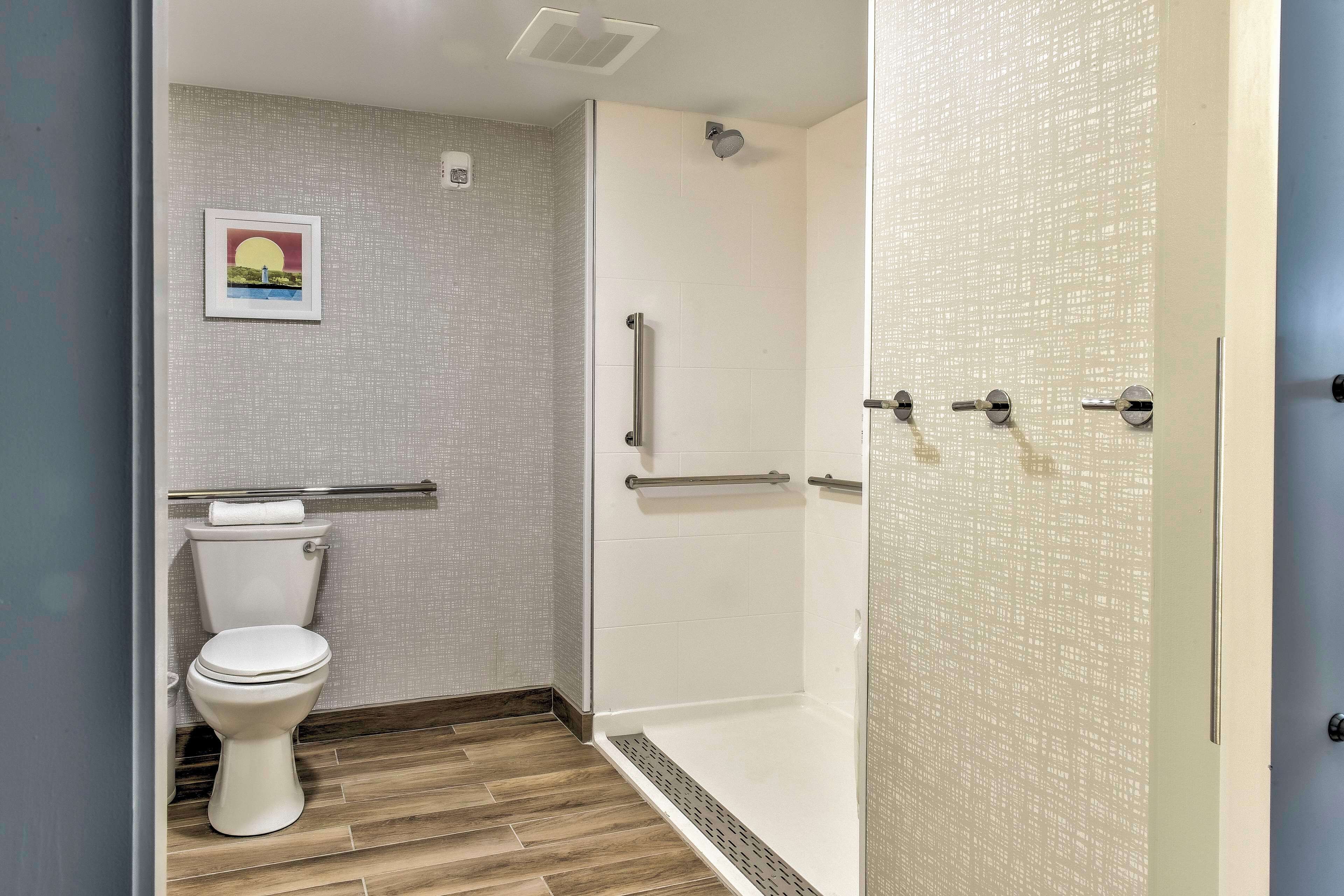 Un baño con inodoro, ducha con puerta de cristal y un perchero para toallas.