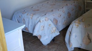 Un dormitorio con dos camas, un aparador blanco y obras de arte en las paredes.