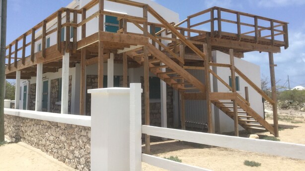 Un edificio de dos pisos con un balcón de madera y una escalera.