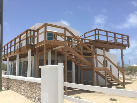 A two-story building with a wooden deck and a staircase.