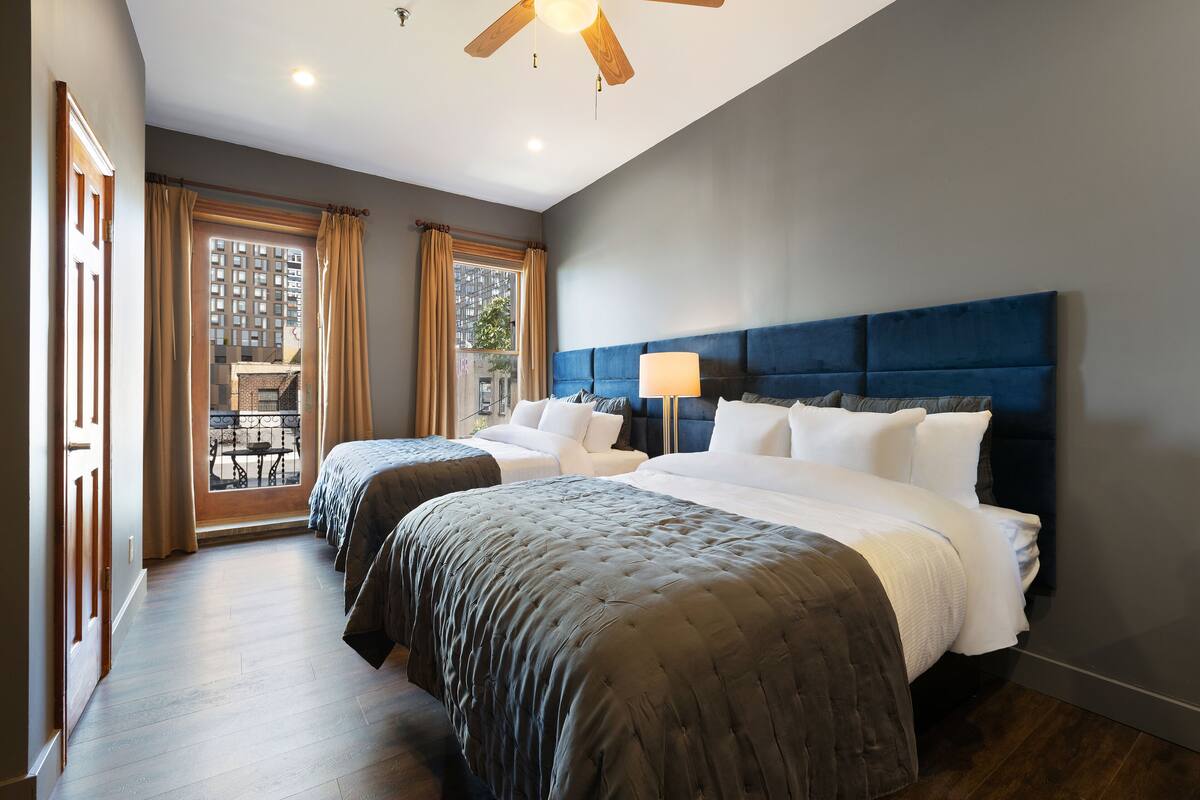 Een hotelkamer met twee bedden, een groot raam en een plafondventilator.