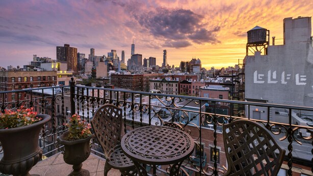 Une terrasse sur le toit offrant une vue panoramique sur la ville, avec une table et des chaises.