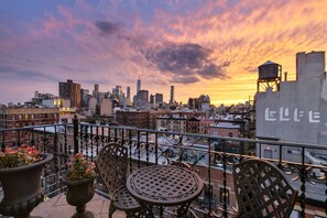 Een terras op het dak met uitzicht op de skyline van de stad, een tafel en stoelen.