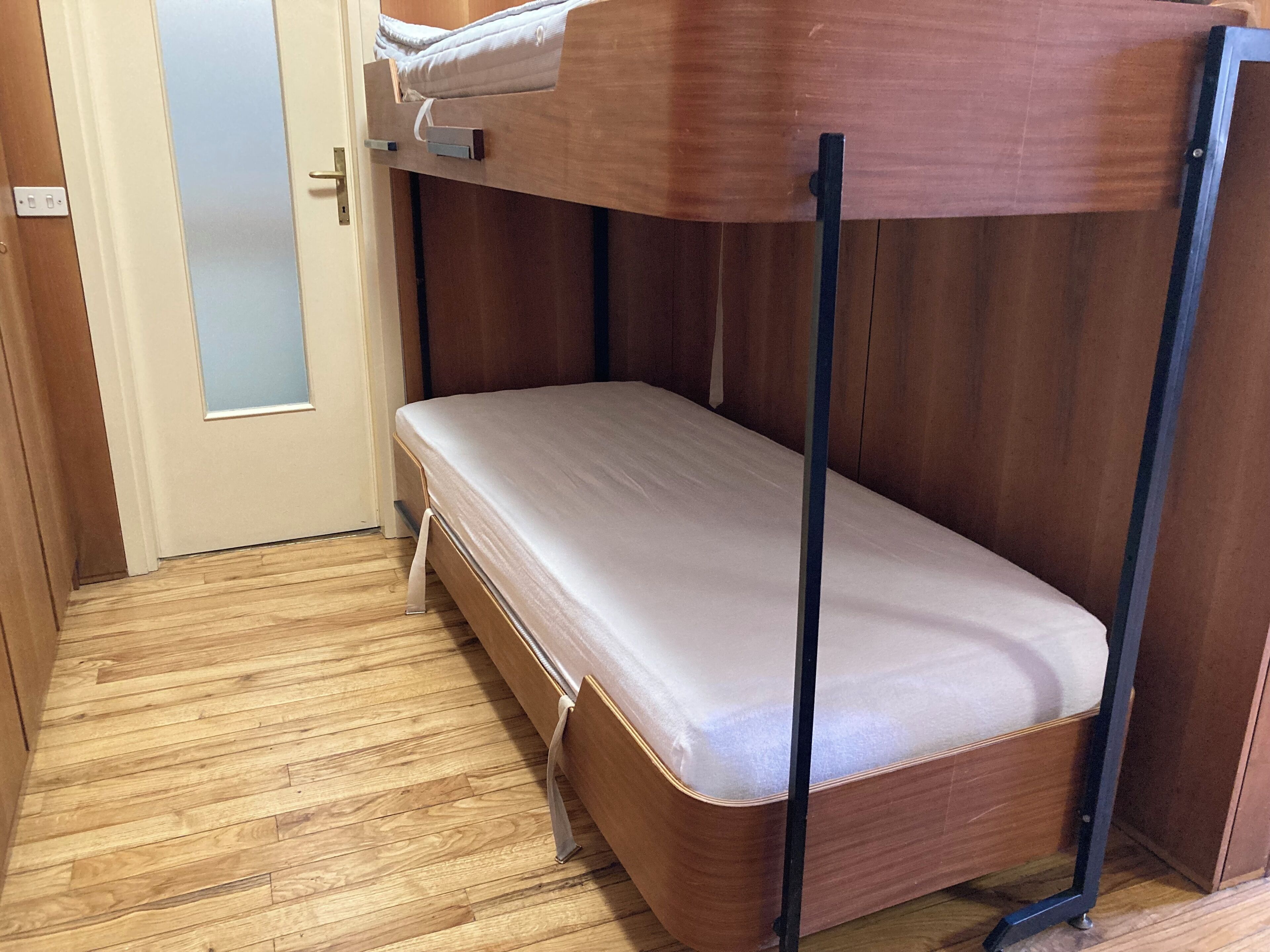 Une petite pièce, de taille modeste, avec un lit superposé et une porte.