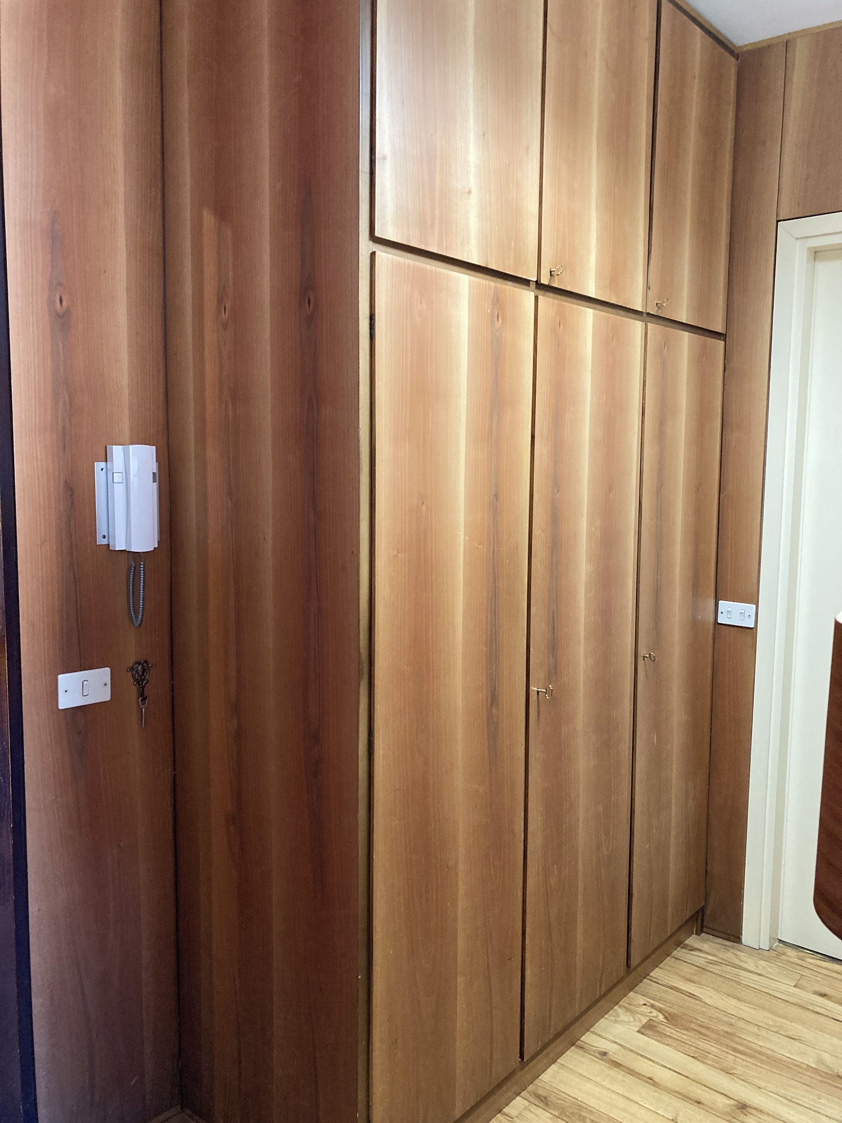 Een kamer met houten lambrisering, een witte deur en een lichtschakelaar op de muur.