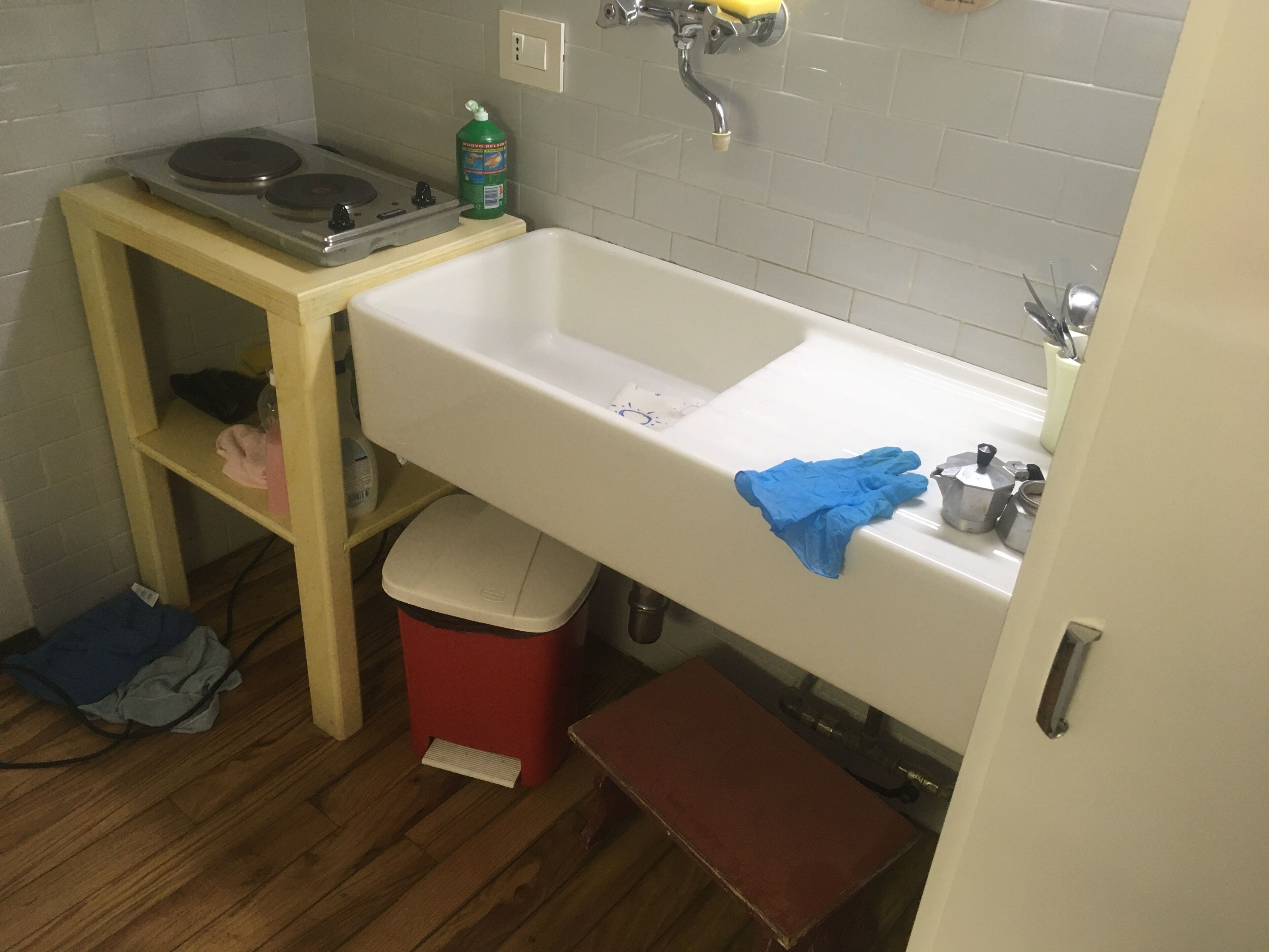 Un baño pequeño con lavamanos, inodoro y estante de madera.