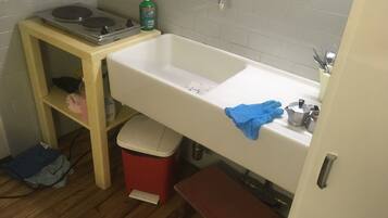 Un baño pequeño con lavamanos, inodoro y estante de madera.