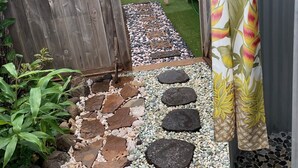 A garden pathway with stepping stones leading to a wooden fence.