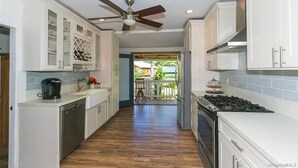 A kitchen with white cabinets, a gas stove, a dishwasher, and a ceiling fan.