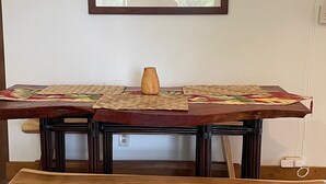 A wooden table with a woven placemat, a vase, and a framed picture on the wall behind it.