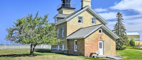 A historic brick building with a prominent tower and a small adjacent structure labeled 'Light House Tours Start Here.'