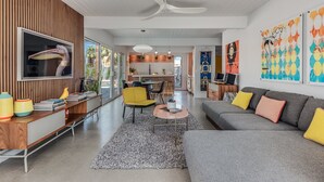 A modern living room with a grey sofa, yellow armchair, and a dining area with a wooden table. - Dreamy Mid Century Modern House with Saltwater Pool &  Resort Style Backyard (Palm Springs)
