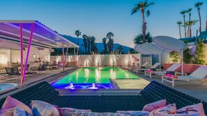 A pool area with lounge chairs, a covered seating area, and a view of palm trees and mountains. - Dreamy Mid Century Modern House with Saltwater Pool &  Resort Style Backyard (Palm Springs)