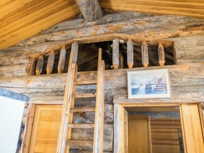 A wooden cabin interior with a wooden ladder, a framed picture, and wooden doors. - Rukanjurmu 7 by Interhome (Kuusamo)