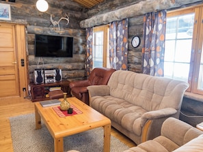 Una sala de estar acogedora con televisor, sofá de cuero y una mesa de centro de madera.