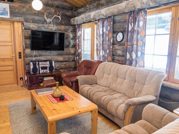A cozy living room with a television, leather sofa, and a wooden coffee table.