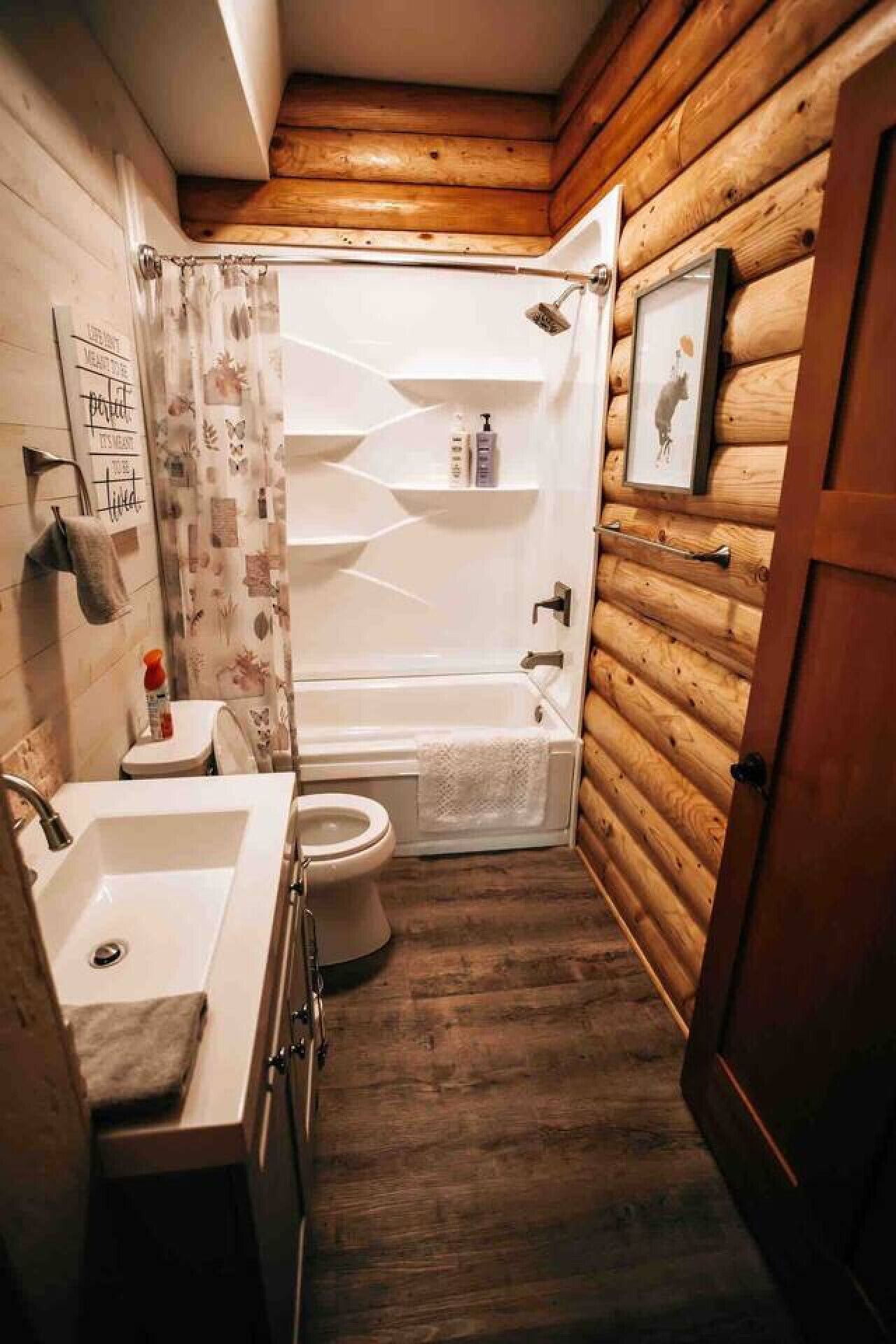 Ein Badezimmer mit Holzeinrichtung, einer Dusche, einer Toilette und einem Waschbecken mit Handtuch.