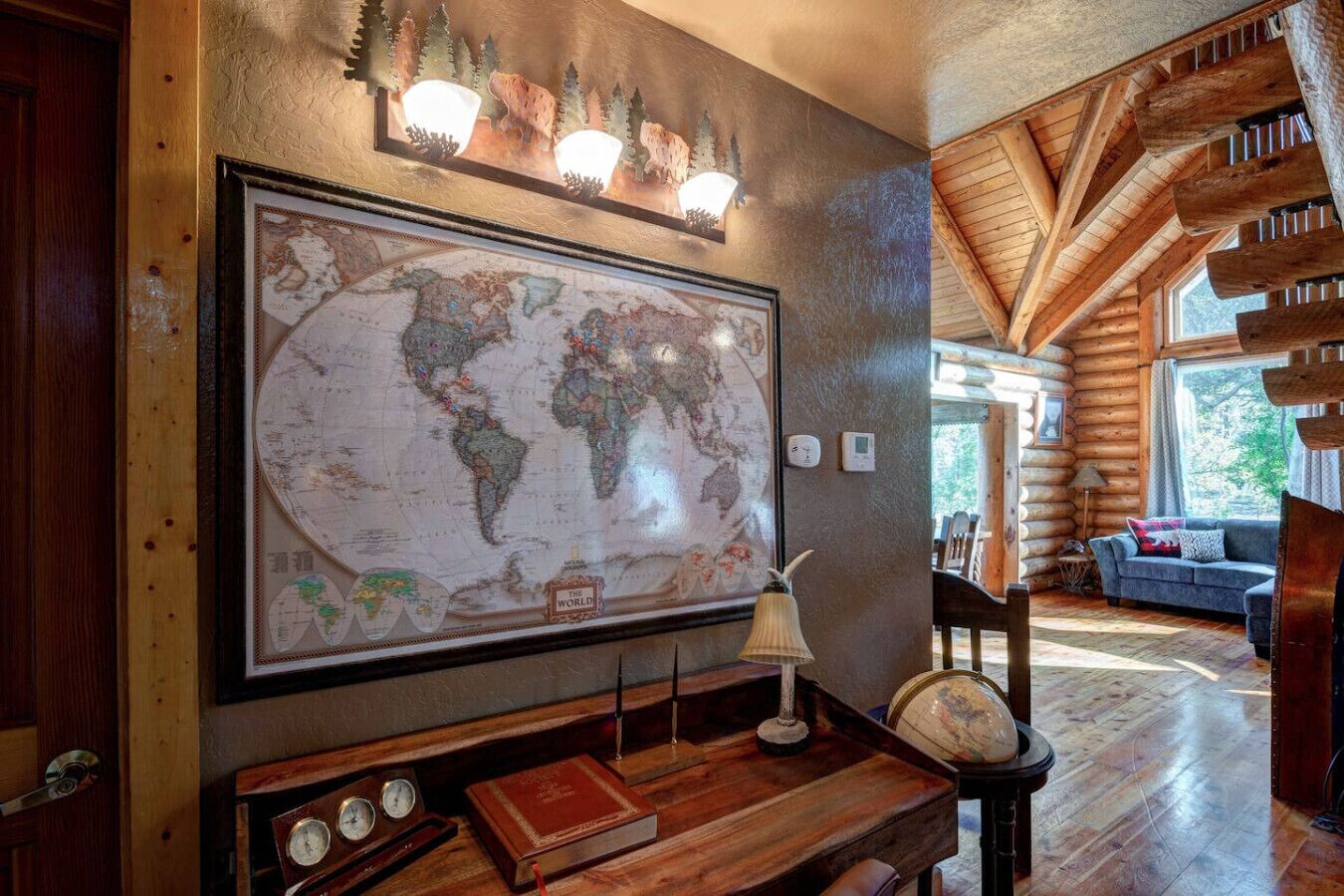 A large world map on the wall, a wooden bench, a globe, a lamp, and a cozy seating area with a sofa.