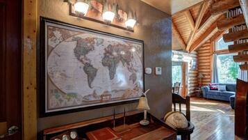 A large world map on the wall, a wooden bench, a globe, a lamp, and a cozy seating area with a sofa.