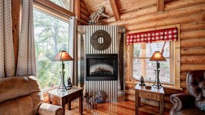 Interior acogedor de una cabaña de troncos con chimenea, sofás de cuero y pisos de madera.