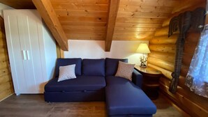 Una habitación acogedora con un sofá modular, una mesita con una lámpara y un armario blanco.