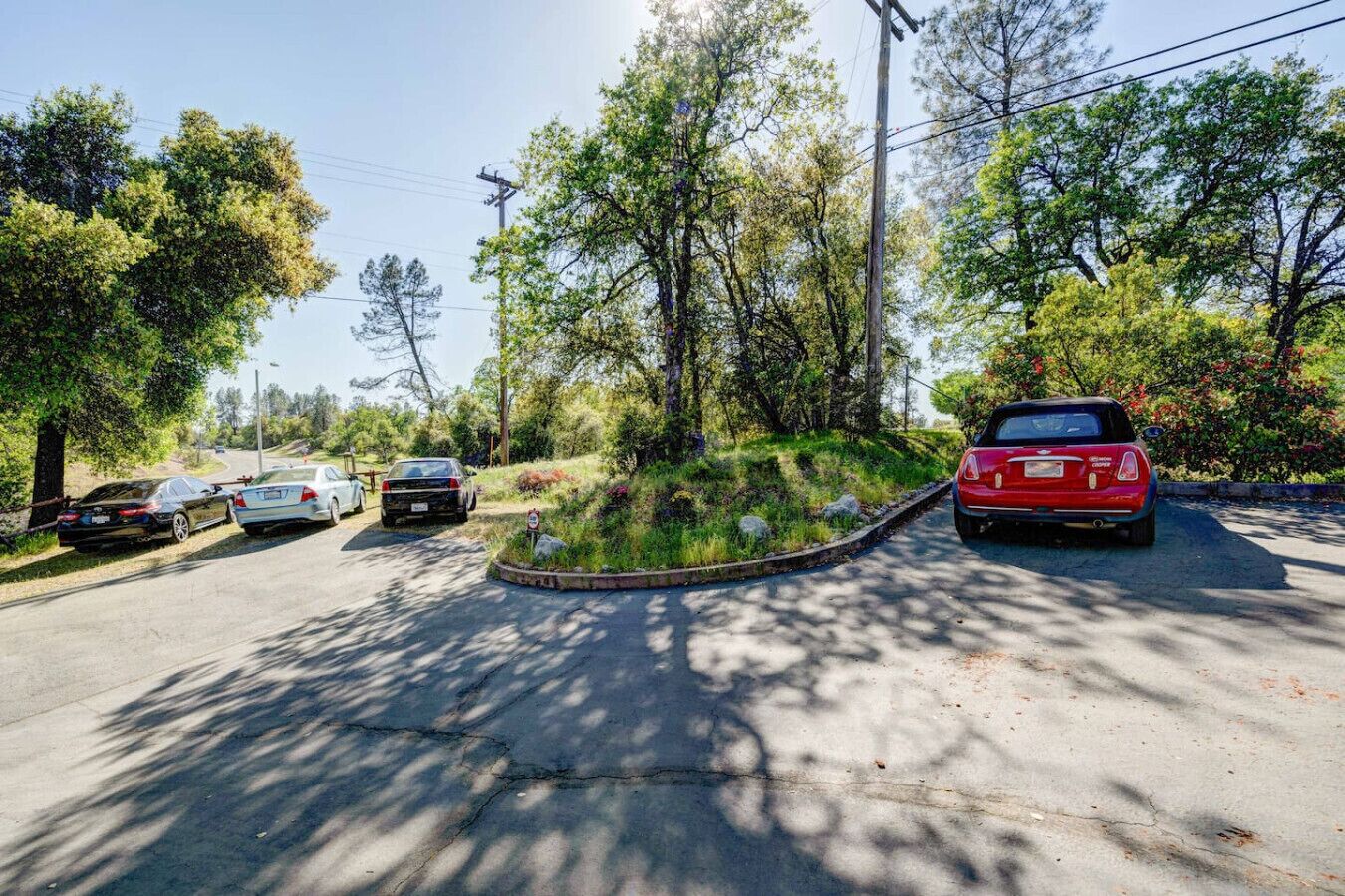 Ein Parkplatz mit parkenden Autos an der Seite einer Straße, umgeben von Bäumen und Grün.