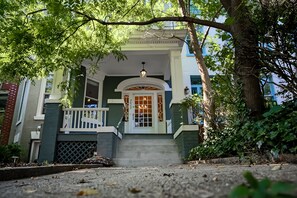 A two-story house with a porch, a white door, and a small staircase leading to the entrance. - "Luxury spacious charming DC row house + parking" (Washington dc)