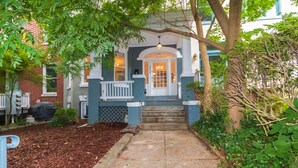 A house with a front porch, steps leading to the door, and a small garden area with mulch and plants.
