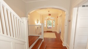 A hallway with wooden flooring, white walls, and a white door on the right.