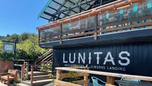 En trækonstruktion med et skilt, der viser "LUNITAS Mexican Bakery & Gibbons Landing".
