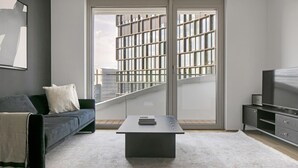 A modern living room with a grey sofa, a coffee table, and a TV on a wooden cabinet. - Modern Wieden 1BR w/ Balcony, Gym, Elevator, walk to U-Bahn, by Blueground (Vienna)