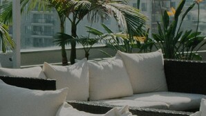 Un balcon avec un canapé, des coussins et des plantes en pot.